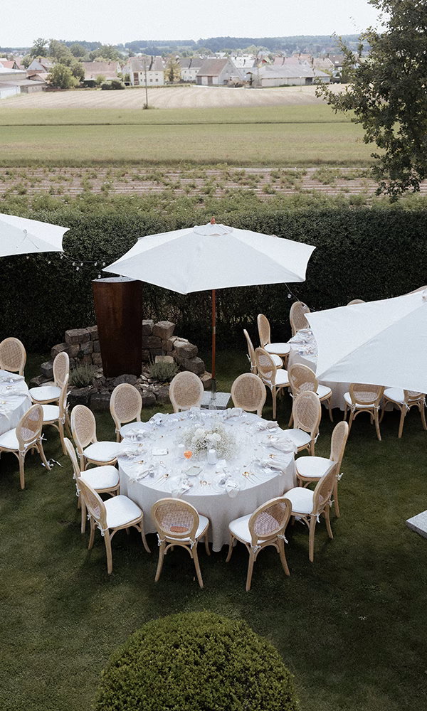 Outdoor-Setting mit festlich dekorierten Tischen vor ländlicher Kulisse.