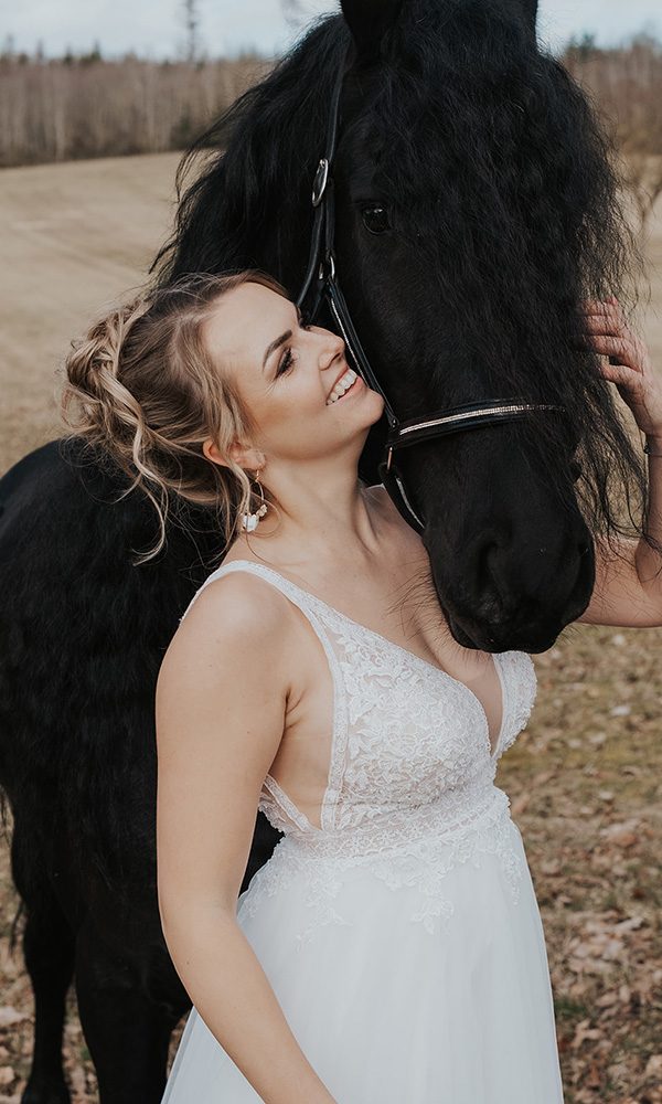 Inniger Moment zwischen Braut und Friesenpferd auf freiem Feld.