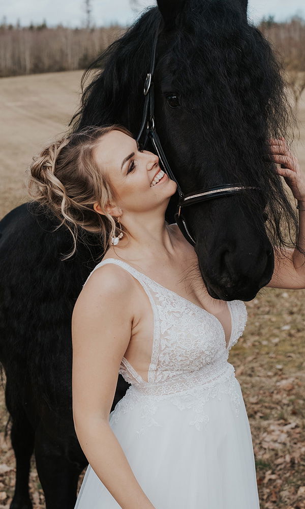 Inniger Moment zwischen Braut und Friesenpferd auf freiem Feld.