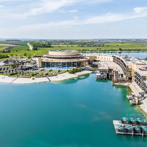 Panoramablick auf ein modernes Resort am Wasser mit grüner Umgebung.