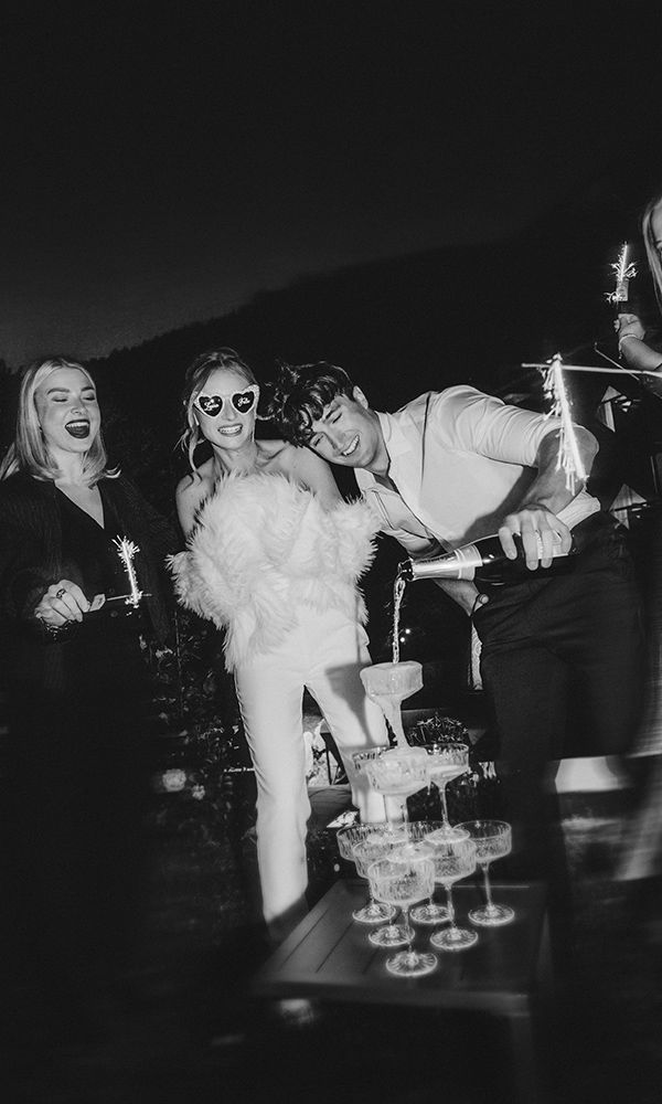 Gäste stoßen mit funkelnden Gläsern und einem Champagnerturm im Hintergrund an.