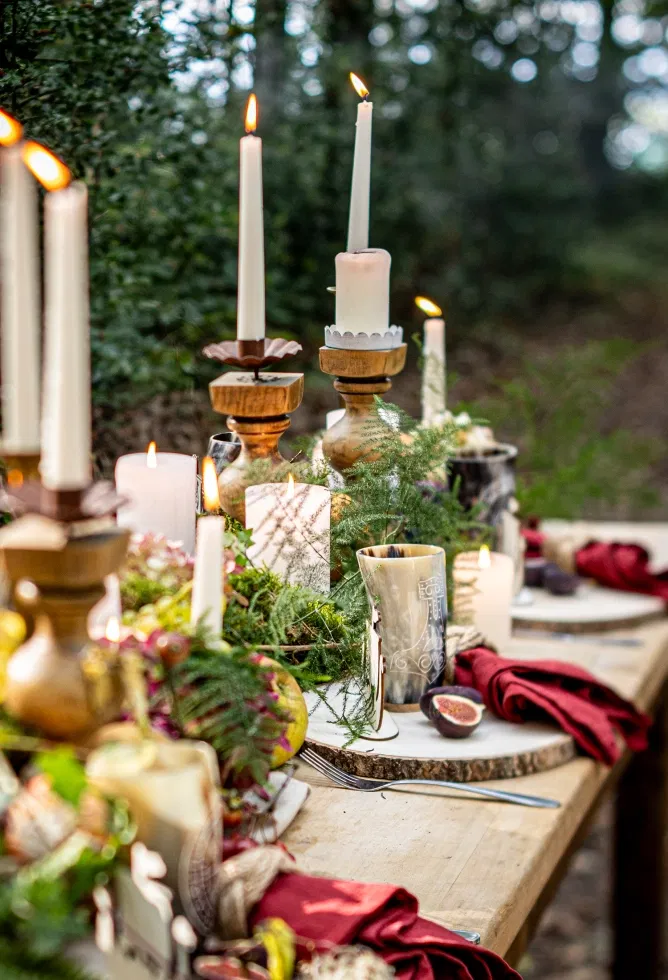 Detailaufnahme einer Wikinger Hochzeitstafel mit Kerzen, Tannengrün, Beeren und rustikalem Geschirr