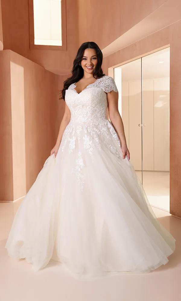 Elegantes Curvy-Brautkleid mit V-Ausschnitt, Spitzenoberteil und zartem Tüllrock – romantisch und figurschmeichelnd zugleich.
