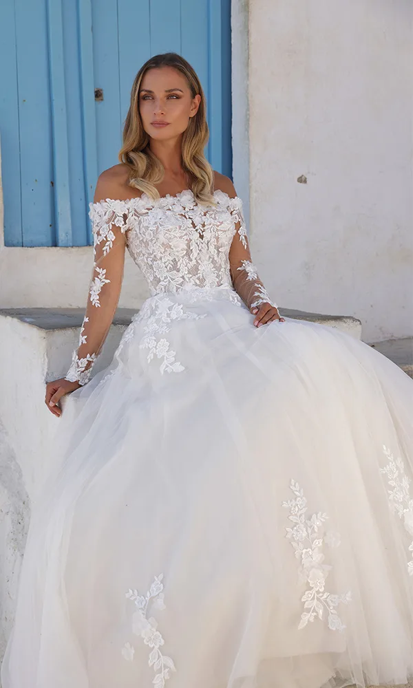 Romantisches Off-Shoulder-Brautkleid mit transparenter Spitze und floralen 3D-Applikationen, kombiniert mit einem weit ausgestellten Tüllrock.