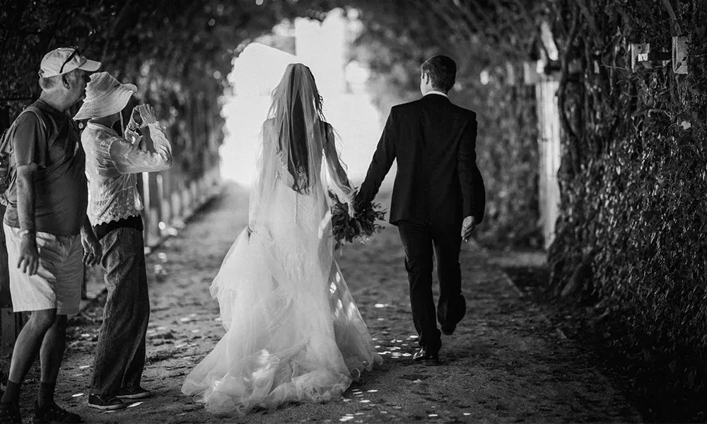 Braut und Bräutigam gehen durch Laubengang,