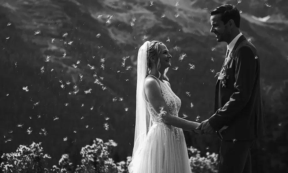 Traumhaftes Hochzeitsfoto: Brautpaar umgeben von tanzenden Pusteblumensamen.