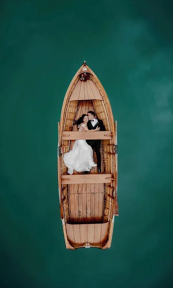 Brautpaar liegt verliebt in einem Holzboot auf türkisfarbenem Wasser.