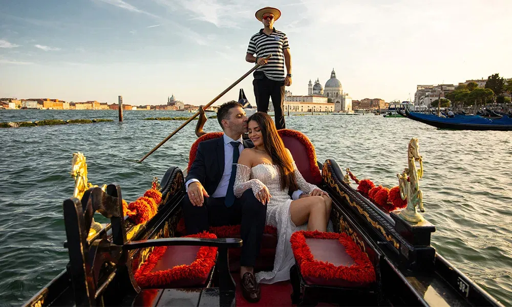 Verliebtes Brautpaar in einer venezianischen Gondel bei Sonnenuntergang.