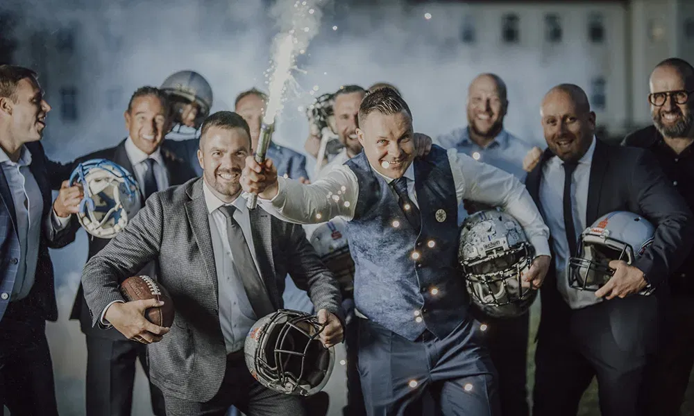 Bräutigam und Freunde feiern mit Footballhelmen und Pyrotechnik.