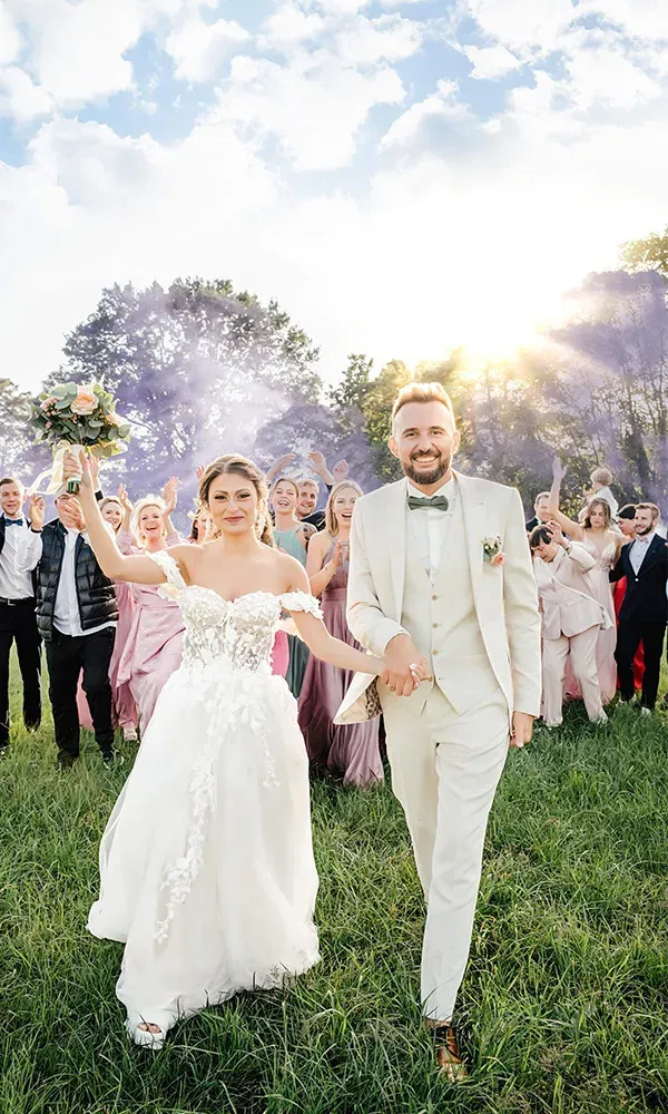 Braut und Bräutigam ziehen fröhlich mit ihren Gästen ein.