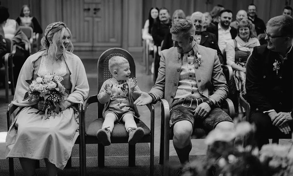 Kleiner Junge gibt seinem Vater ein High Five während der Trauung im Standesamt.