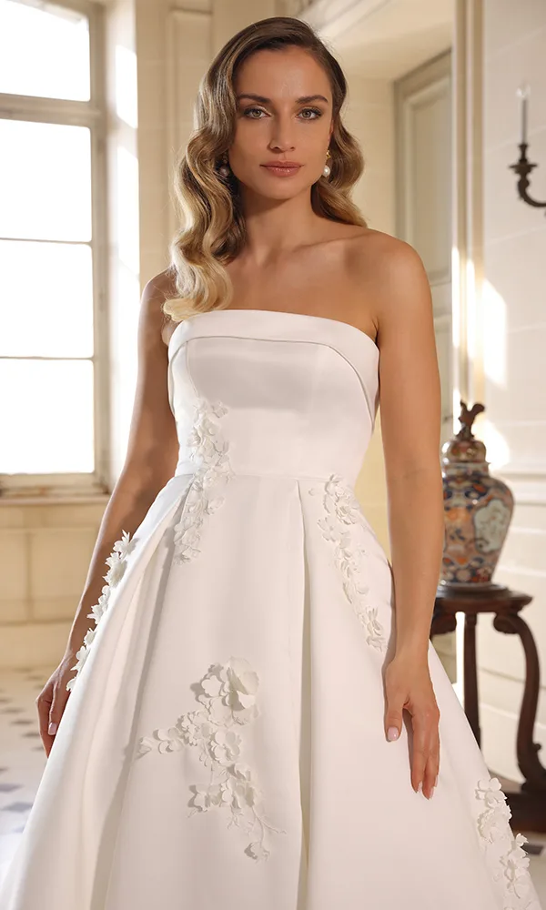 Schulterfreies A-Linien-Brautkleid mit floralen 3D-Applikationen auf dem Rock – klassisch und modern zugleich.