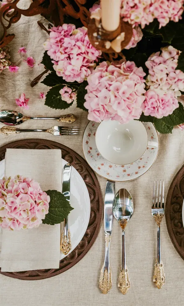 Eleganter Tisch für die Hochzeitsfeier mit rosa blühenden Hortensien und stilvollem Porzellan.