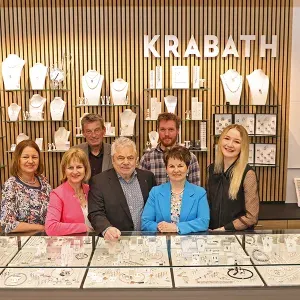 Teamfoto der Mitarbeitenden des Juweliergeschäfts Krabath vor der Schmuckauslage im Laden.