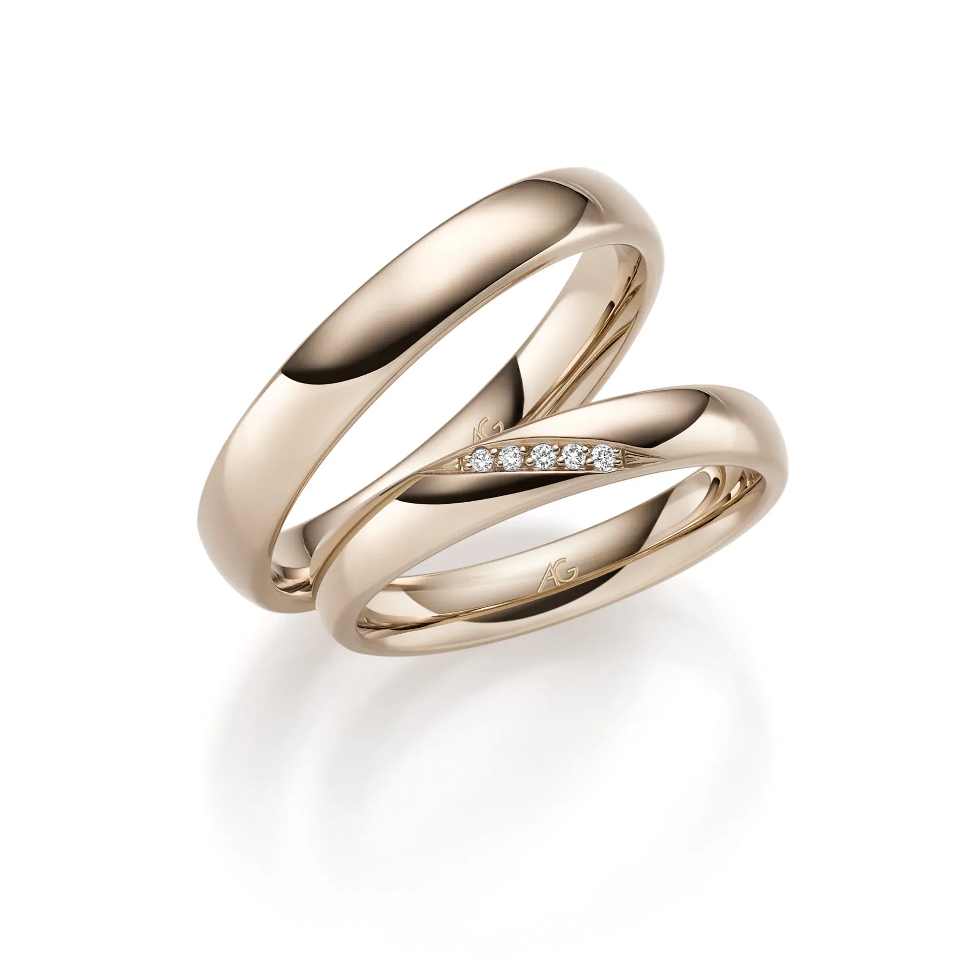 Klassisch glänzende Eheringe aus poliertem Haselnussgold mit funkelnden Diamanten im Damenring.