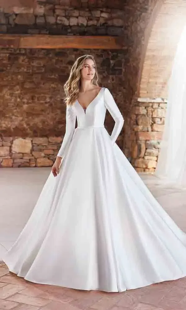 Klassisches Hochzeitskleid mit weitem Rock und tiefem Dekolleté, getragen in historischem Ambiente.