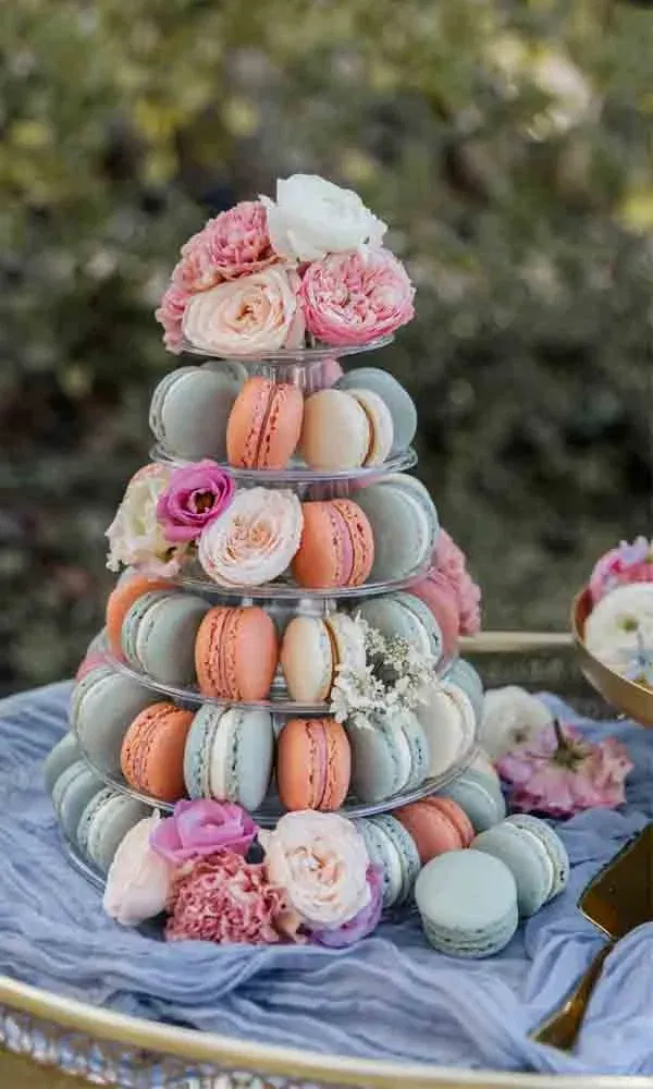Macaron-Pyramide in Mint, Apricot und Creme mit frischen Blumen als romantisches Highlight auf einem Sweet Table.