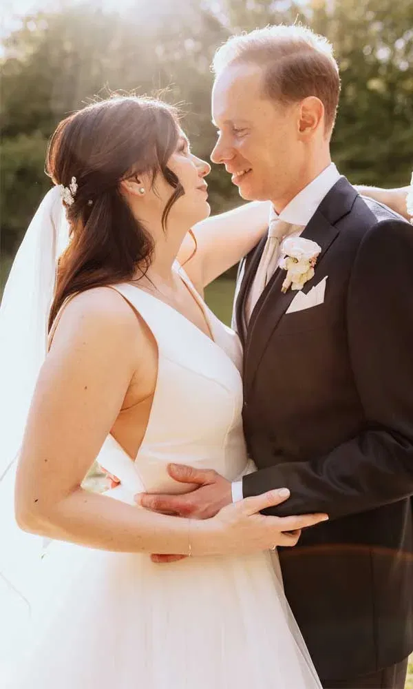 Inniger Moment zwischen Braut und Bräutigam im Freien – Sonnenstrahlen tauchen die Szene in warmes Licht.