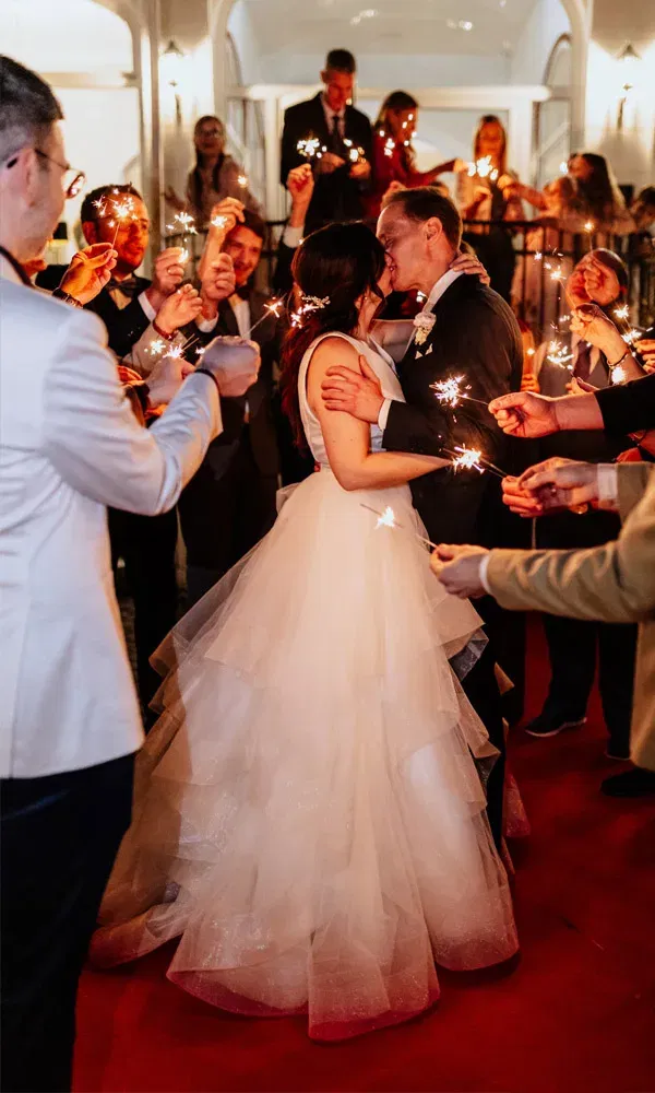 Ein Kuss unter Wunderkerzen: Das Brautpaar feiert mit seinen Gästen in stimmungsvoller Abendkulisse.