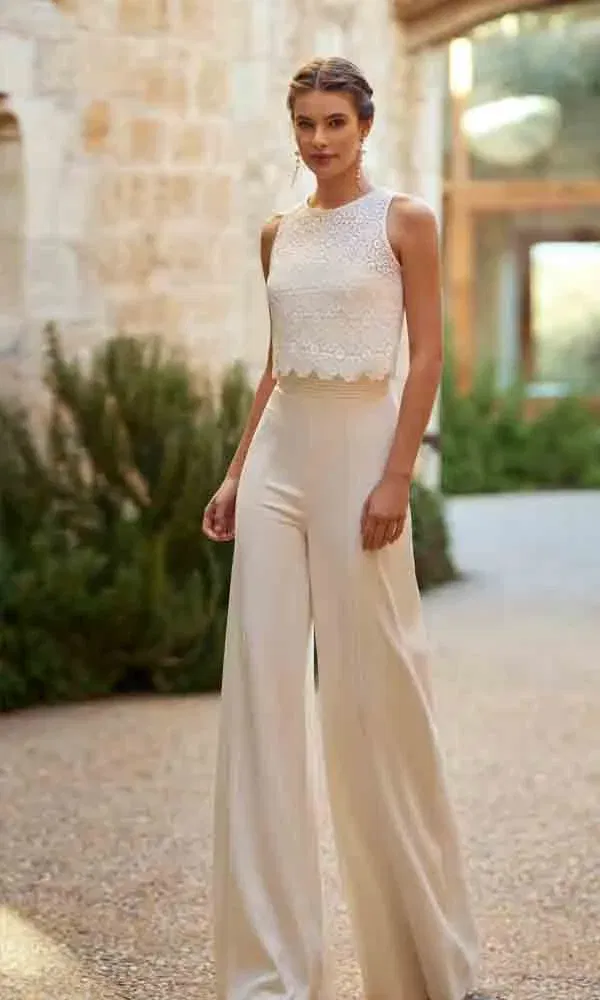 Moderner Hochzeitslook mit ärmellosem Spitzenoberteil und fließender Palazzo-Hose – fotografiert im Innenhof.