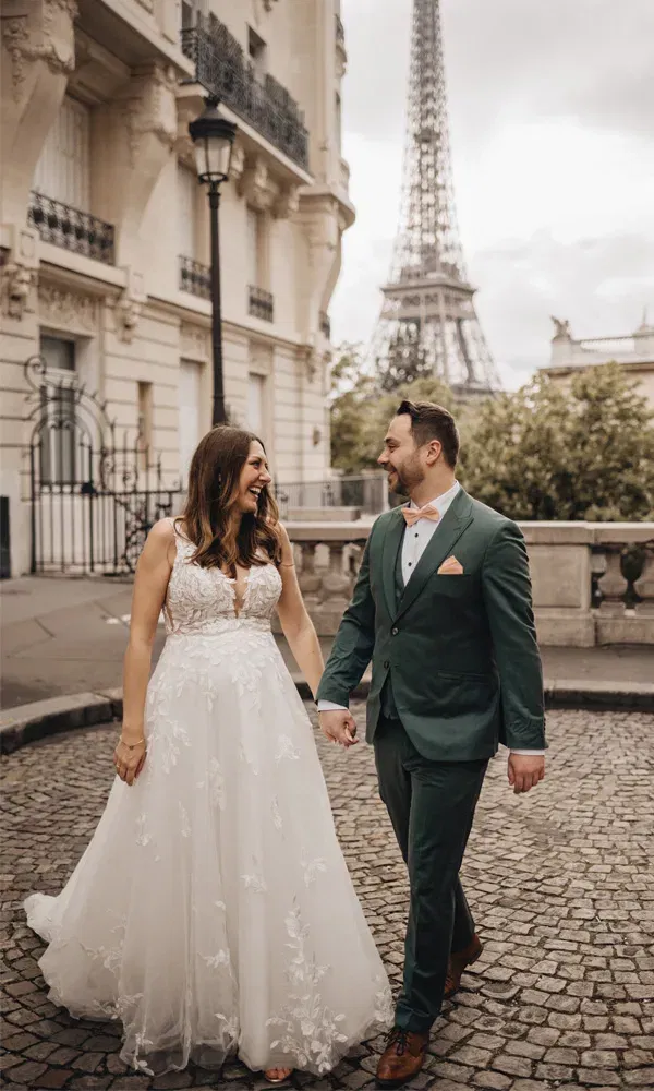 Hand in Hand schlendern Braut und Bräutigam lachend durch die Pariser Altstadt.