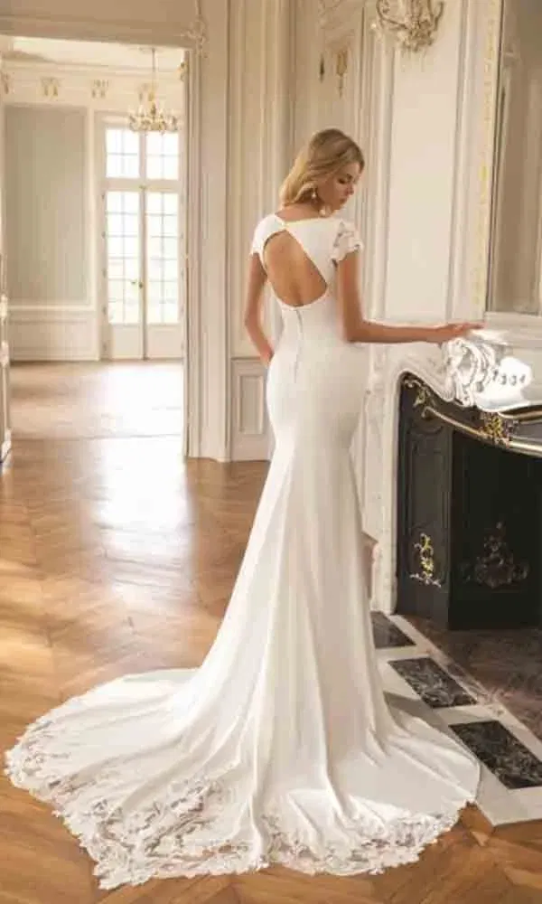 Modernes Fit-and-Flare-Brautkleid mit kurzem Ärmel und tiefem Rückenausschnitt – kombiniert mit schlichter Eleganz und feiner Spitze.