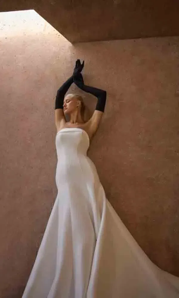 Modernes Fit-and-Flare-Brautkleid mit cleanem Look, kombiniert mit schwarzen langen Handschuhen in künstlerischer Pose.