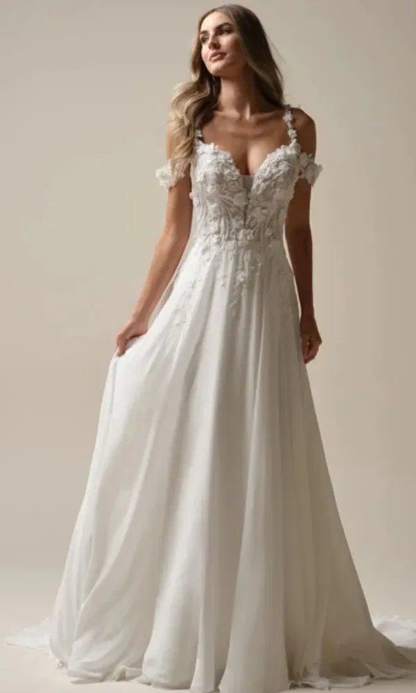 Elegantes Brautkleid mit floral besticktem Mieder, Herzausschnitt und locker fallendem Chiffonrock – Braut blickt verträumt zur Seite.