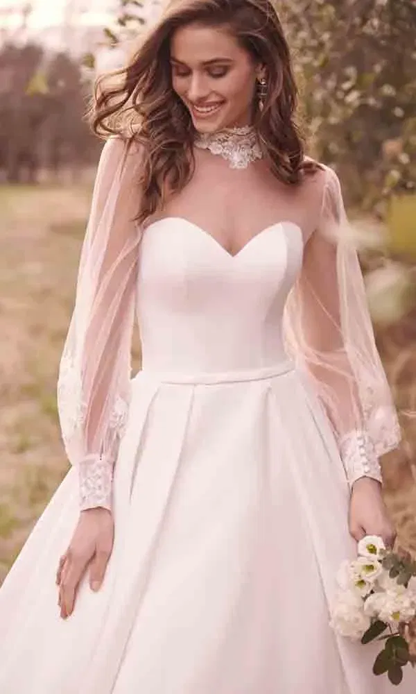 Elegantes Hochzeitskleid mit abnehmbaren Ärmeln und Spitzenkragen bei einer Outdoor-Trauung.