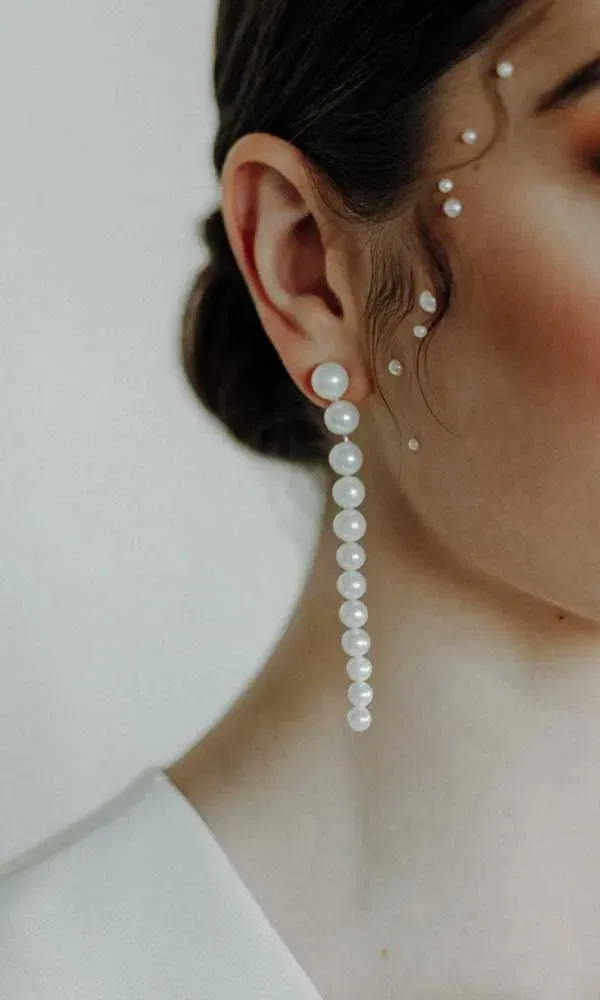 Detail einer Braut mit elegantem Ohrschmuck aus Perlen und zarten Perlen auf der Haut