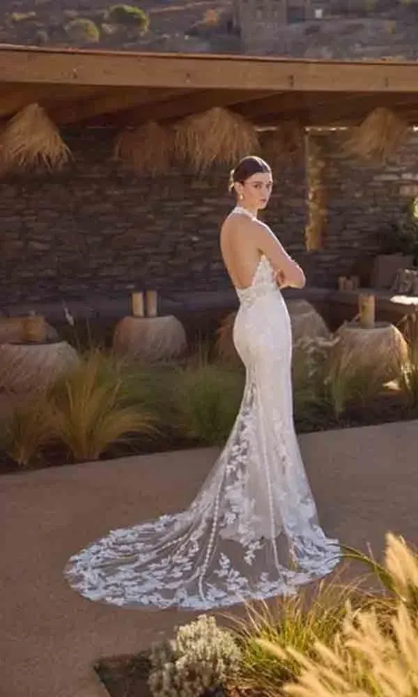 Rückenfreies Mermaid-Kleid mit feiner Spitze und langer transparenter Schleppe – aufgenommen in mediterraner Abendstimmung.