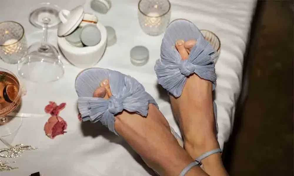Elegante Brautschuhe mit Schleifen in „Something Blue“, inszeniert auf einer festlich gedeckten Hochzeitstafel mit Licht und Snacks.