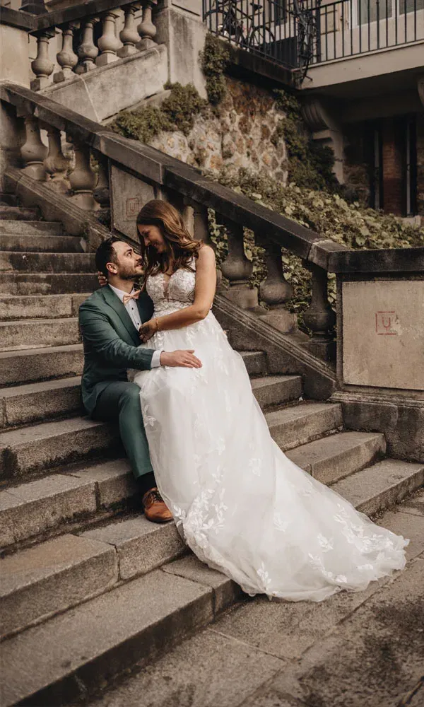 Auf einer alten Steintreppe in Paris teilt das Brautpaar einen stillen Moment der Nähe.