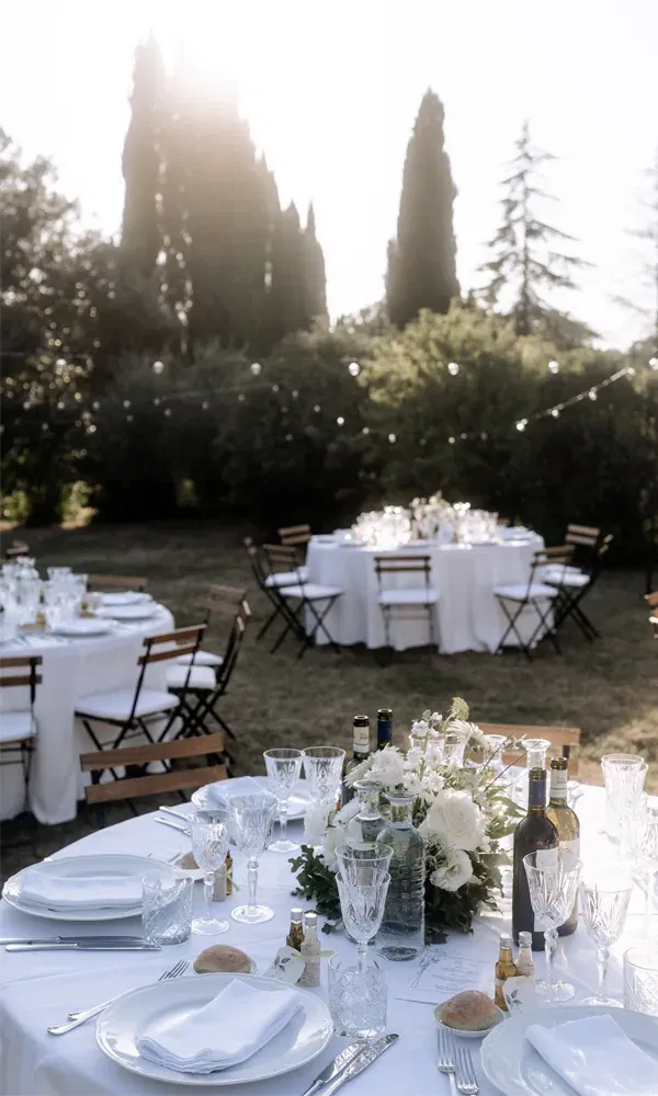 Elegante Hochzeitstafel unter freiem Himmel, liebevoll dekoriert mit weißen Blumen und stilvollem Gedeck.