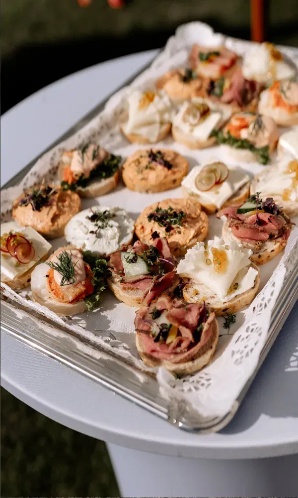 Appetitanregende Auswahl an kleinen Snacks, liebevoll angerichtet auf einem Tablett mit Spitzenpapier.