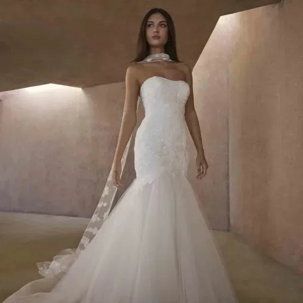 Schlanke Braut trägt ein figurbetontes Mermaid-Hochzeitskleid mit floraler Spitze und ausgestellter Tüll-Schleppe.