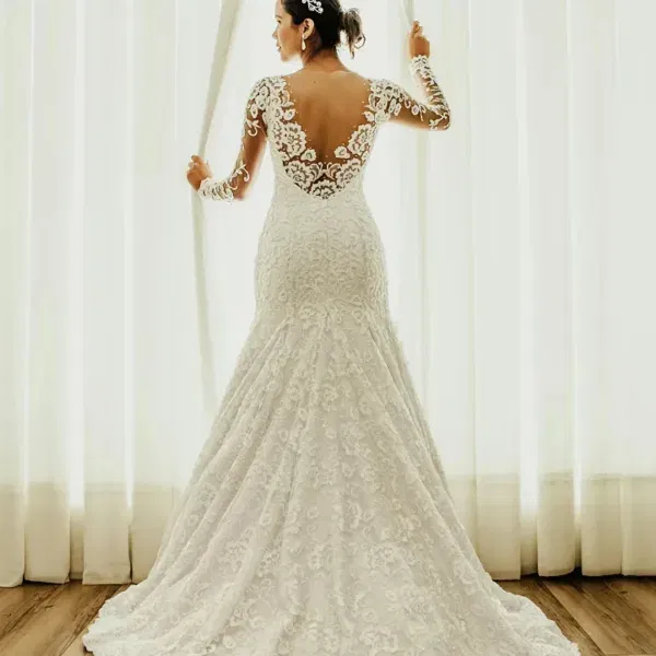 Rückansicht einer kurvigen Braut in einem figurbetonten Brautkleid aus floraler Spitze mit langen Ärmeln und freiem Rücken.