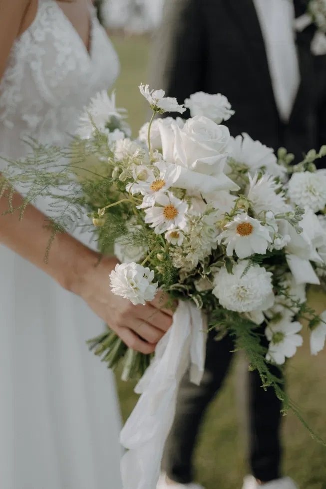 Natürlicher Brautstrauß mit weißen Blumen, feiner Greenery und locker gebundenem Seidenband