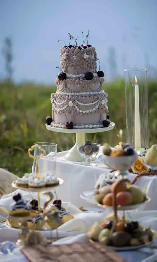 Aufwendig dekorierte Festtagstorte mit Kirschen, flankiert von Dessert-Etageren und Kerzen.