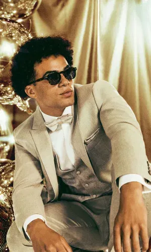 Moderner Hochzeitslook: Eleganter Wilvorst-Anzug in Beige mit Fliege und Weste, stilvoll ergänzt durch eine Sonnenbrille.