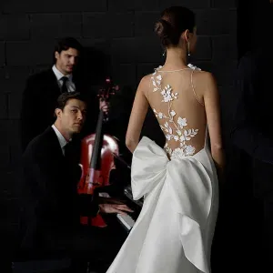 Moderne Brautmode: Rückenfreies Kleid mit Stickereien und Statement-Schleife aus der Aire Atelier 2026-Kollektion.