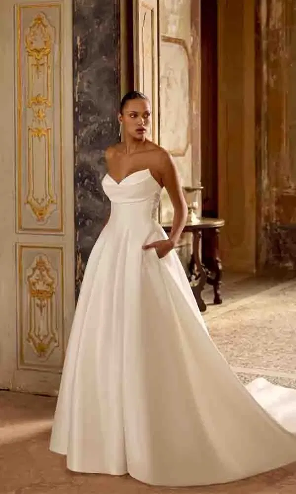 Zeitloses Hochzeitskleid mit schlichtem Oberteil, tiefem Dekolleté und weitem Rock im Ballkleid-Stil.