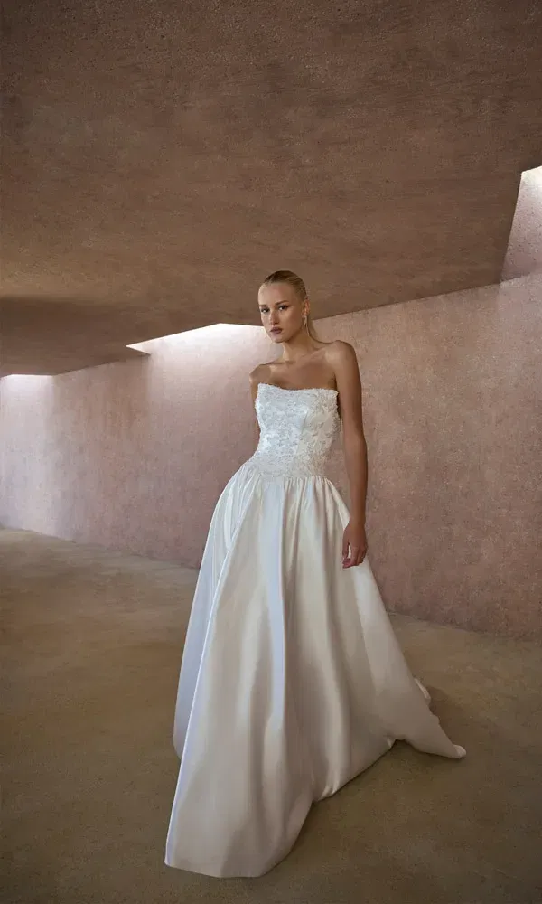 Elegantes Hochzeitskleid mit trägerlosem Spitzenoberteil und weitem Rock für einen modernen Look.