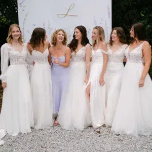 Designerin Sanna Lindström steht lächelnd mit sechs Models in weißen Brautkleidern vor dem Logo der „Villa Lindström“.