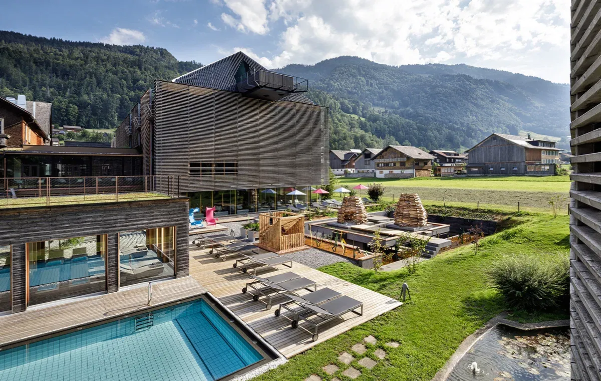 Außenansicht des Genießerhotels GAMS im Bregenzerwald mit Pool, moderner Architektur und Bergpanorama.