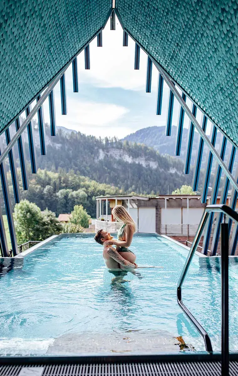 Romantischer Moment im Sky-Pool des Hotels GAMS in Bezau – Paar genießt Wellness mit Blick auf die Berge.
