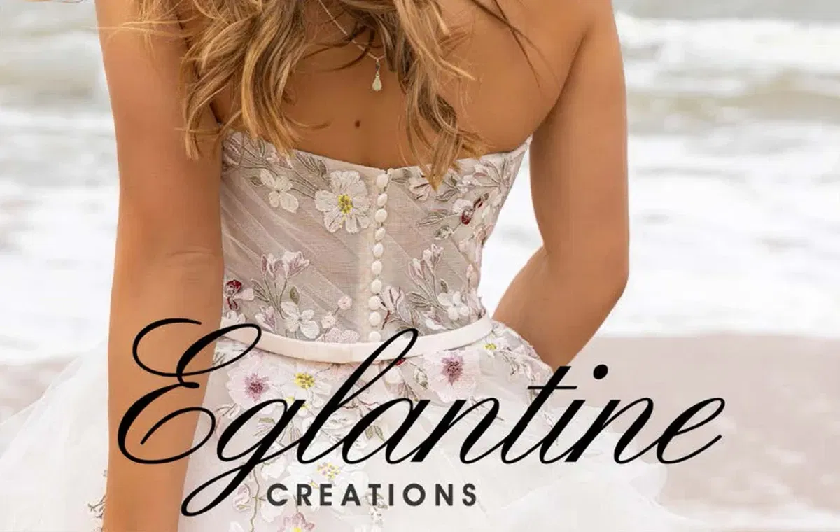 Banner von Eglantine. Es ist eine Braut im Brautkleid am Strand zu sehen