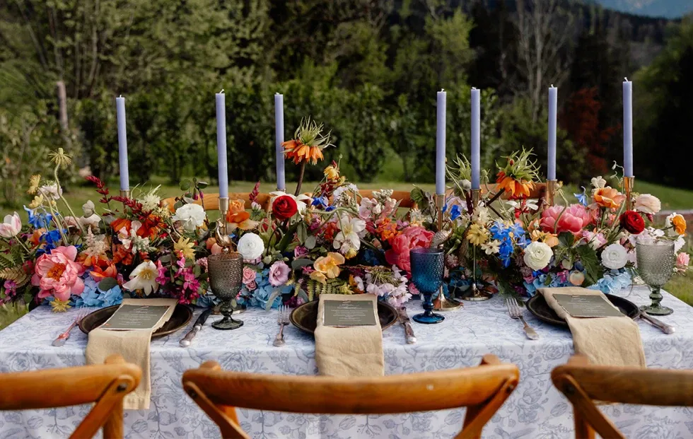 Aufwendig gedeckte Hochzeitstafel mit buntem Blumenschmuck und Kerzen – inspiriert von einer Nature Wedding.