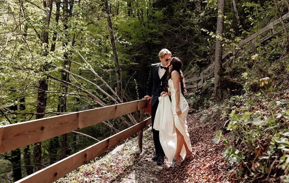 Zärtlicher Kuss im Wald – das Brautpaar genießt die Ruhe der Natur bei seiner Outdoor-Hochzeit.