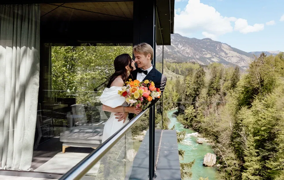 Brautpaar auf modernem Balkon mit Blick auf grüne Berge – Symbol einer eleganten Nature Wedding.